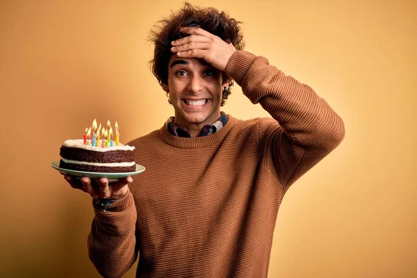 Młody Przystojny Mężczyzna Trzymający Tort Urodzinowy Stojący Nad Odizolowanym Żółtym — Zdjęcie stockowe