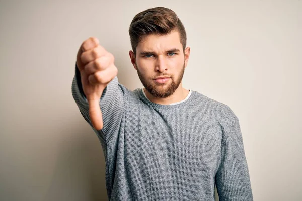 ひげと青い目をした若いハンサムなブロンドの男は カジュアルなセーターを着て 不満と怒って拒絶を示し 親指ダウンジェスチャーで陰性です 悪い表現 — ストック写真