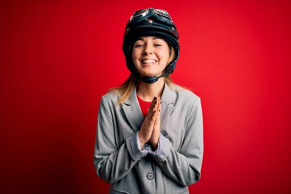 若いです美しいですブロンドオートバイの女性身に着けていますオートバイヘルメット以上赤背景祈るとともに願います許し笑顔自信 — ストック写真