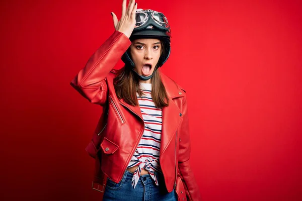 若い美しいブルネットのオートバイのヘルメットと赤いジャケットを身に着けているオートバイの女性は 間違いのために頭の上に手で驚いて エラーを覚えている 忘れられた悪い記憶の概念 — ストック写真