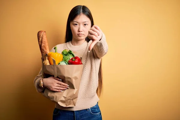 Mladá Asiatka Drží Papírový Sáček Čerstvými Zdravými Potravinami Nad Žlutým — Stock fotografie