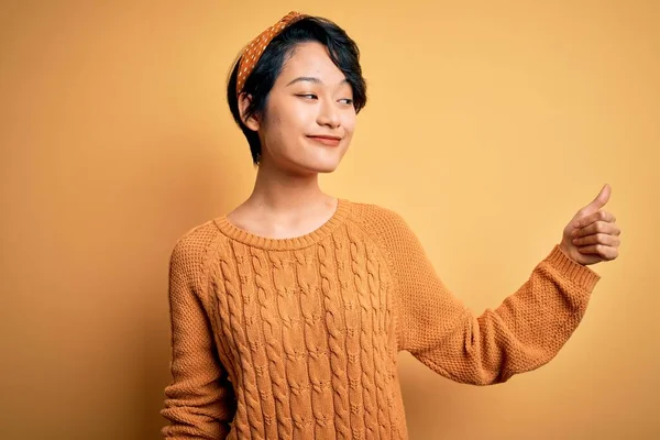 미국식 스웨터를 아리따운 동양인 소녀는 자랑스럽게 엄지손가락을 치켜들며 미소짓고 — 스톡 사진