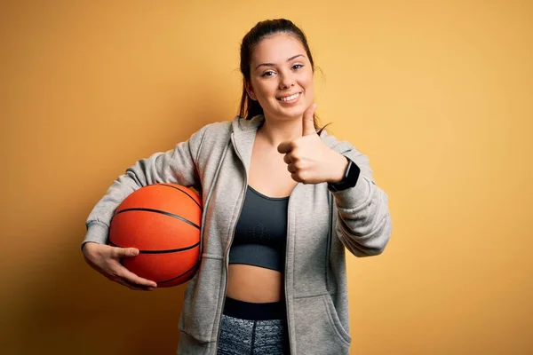 Jovem Bela Morena Esportista Segurando Bola Basquete Sobre Fundo Amarelo — Fotografia de Stock