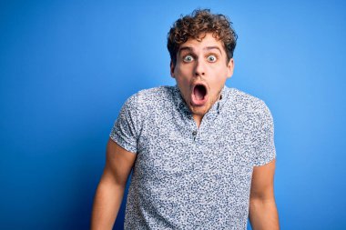 Sarışın, yakışıklı, tatilde, kıvırcık saçlı, sıradan polo giyen, korkmuş ve şok olmuş genç bir adam..