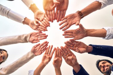 Bir grup işçi ofiste parmaklarıyla sembol çiziyor.