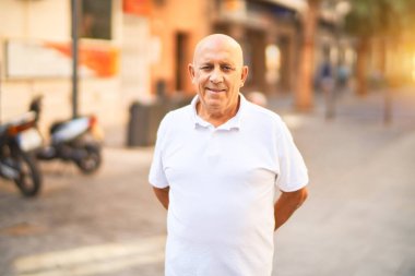 Kıdemli yakışıklı adam mutlu ve kendinden emin gülümsüyor. Kasaba caddesinde yüzünde gülümsemeyle dikilirken