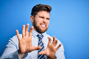 Sakallı, mavi gözlü, şık gömlekli ve kravatlı genç bir iş adamı tiksinti dolu bir ifade takınıyor ve tiksinti tepki verdiği için tiksindirici ve korkunç bir ifade takınıyor. Eller havada