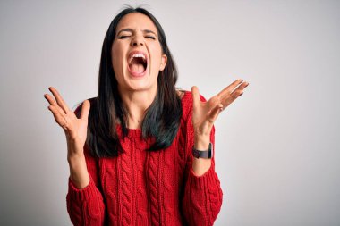 Mavi gözlü genç esmer kadın izole edilmiş beyaz arka plan üzerine gündelik süveter giyerek başarının çılgınlığını kollarını kaldırarak ve gözlerini kapayarak heyecanla bağırarak kutluyor. Kazanan konsept