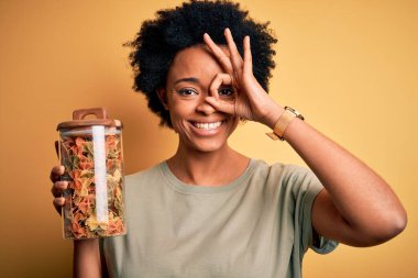 Genç, kıvırcık saçlı, gülümseyen bir İtalyan makarnası şişesi tutan Afro-Amerikalı bir kadın.