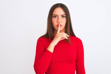 Kırmızı günlük tişört giyen genç ve güzel bir kız izole edilmiş beyaz arka planda dikilip sessiz olmayı diliyor. Sessizlik ve gizli konsept.
