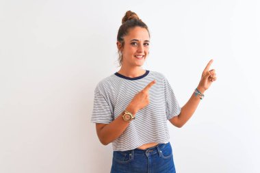 Genç kızıl saçlı modern kadın izole edilmiş arka planda topuz takıyor gülümsüyor ve kameraya bakıyor iki eliyle ve parmaklarıyla kenarı işaret ediyor..