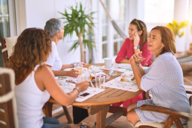 Genç ve güzel bir kız mutlu ve kendinden emin bir şekilde terasta oturmuş bir fincan kahve içiyor.
