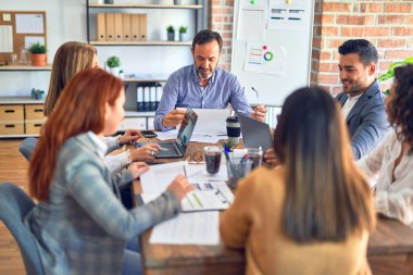 Birlikte çalışan bir grup işçi. Ofiste dizüstü bilgisayarla oturup belgeleri okumak.