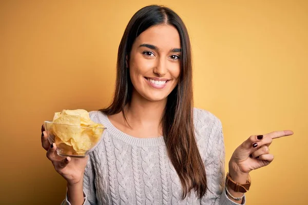 Sarı Zemin Üzerinde Patates Cipsi Olan Genç Güzel Bir Esmer — Stok fotoğraf