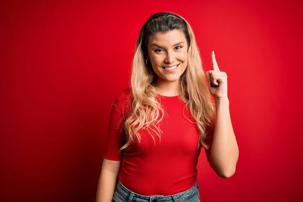 Jovem Mulher Loira Bonita Vestindo Camiseta Casual Sobre Fundo Vermelho — Fotografia de Stock