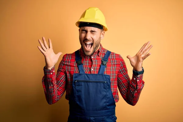 Junger Bauarbeiter Bauuniform Und Schutzhelm Vor Gelbem Hintergrund Feiert Verrückt — Stockfoto