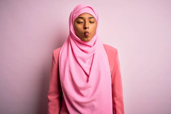 孤立したピンクの背景にイスラム教徒のヒジャーブを身に着けている若いアフリカ系アメリカ人のアフロ女性は 狂気とコミカルなジェスチャーで魚の顔を作ります 面白い表現 — ストック写真