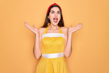 Sarı arka plan üzerine 50 'li yılların moda elbisesi giymiş genç ve güzel bir kadın çılgın ve başarıyı kollarını kaldırıp heyecanla haykırarak kutluyor. Kazanan konsept