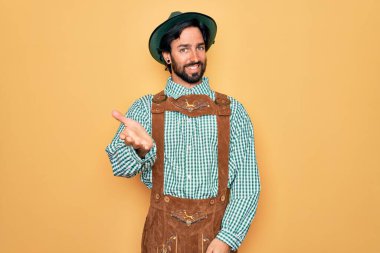 Almanya festivali için geleneksel Alman Ekim Festivali geleneği giyinen yakışıklı genç adam dostça bir selamlama ve hoş geldin hediyesi olarak el sıkışma sunuyor. Başarılı bir iş..