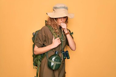 Sırt çantası ve su matarası takan mavi gözlü genç sarışın kaşif hasta ve bronşitin belirtisi olarak öksürüyor. Sağlık hizmeti kavramı.