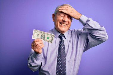 Mor zemin üzerinde bir dolarlık banknot tutan yaşlı, gri saçlı bir adam elleri kafasında, utanç ve şaşkınlık dolu, sinirli ve hayal kırıklığına uğramış bir halde. Hata için korku ve üzüntü.