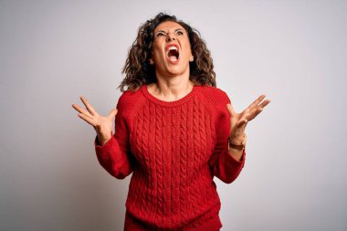 Orta yaşlı esmer kadın izole edilmiş beyaz arka plan üzerinde dikilmiş kızgın, deli deli bağırıyor ve agresif bir ifade ve kollar havada bağırıyor. Hayal kırıklığı konsepti.
