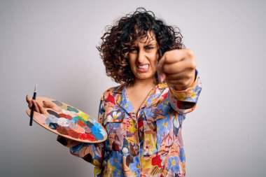 Genç, kıvırcık Arap kadın fırça ve palet kullanarak resim yapıyor. Sinirli ve bıkkın bir şekilde bağırıyor. Öfkeyle bağırıyor.