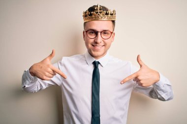 İzole edilmiş arka planda altın taç takan yakışıklı beyaz bir iş adamı. Yüzünde bir gülümsemeyle, kendini gururlu ve mutlu bir şekilde gösteriyor..