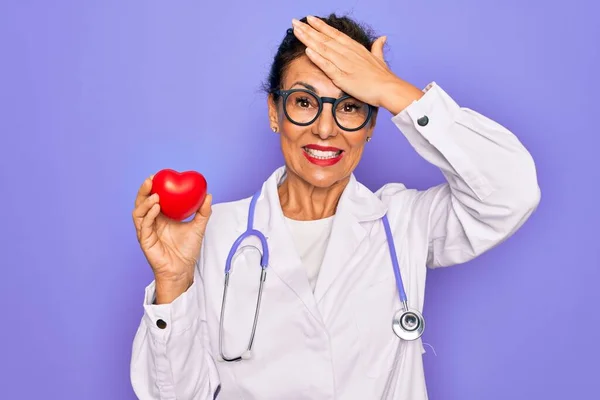 Starszy Kardiolog Średnim Wieku Kobieta Trzymająca Czerwone Serce Fioletowym Tle — Zdjęcie stockowe