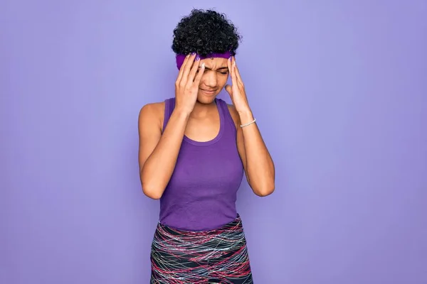 ストレスが原因で頭の痛みのために手を頭の上に紫色の背景にカジュアルなスポーツウェアを身に着けている美しいアフリカ系アメリカ人アフロ女性 片頭痛に苦しむ — ストック写真