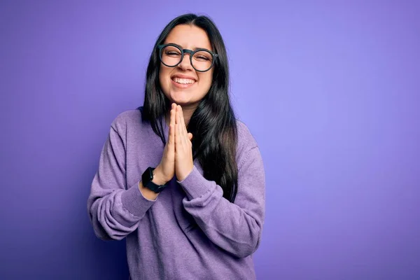 Mujer Morena Joven Con Gafas Sobre Fondo Aislado Púrpura Rezando —  Fotos de Stock