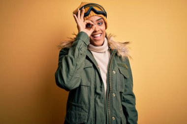 Genç Afrikalı Afro-Amerikan kayakçı kız kar sporu giysisi ve kayak gözlüğü takıyor..