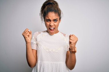 Genç, güzel, Afro-Amerikalı bir kız, beyaz arka planda dikilen rahat tişört giyiyor kızgın ve kızgın yumruklar sallarken öfkeyle bağırıyor. Öfke ve agresif kavram.