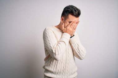 Beyaz tenli arka plan üzerine sıradan bir kazak giyen yakışıklı beyaz bir adam. Ağlarken suratını ellerle kapatan üzgün bir ifade. Depresyon kavramı.