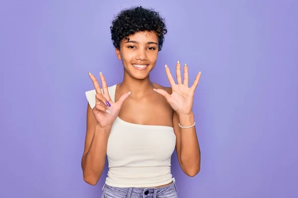 年轻美丽的非洲裔美国女人 身穿紫色背景的休闲T恤 手指头指尖八号 面带微笑 自信而快乐 — 图库照片