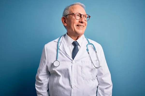 Kıdemli Gri Saçlı Doktor Steteskop Mavi Arka Planda Tıbbi Ceket — Stok fotoğraf