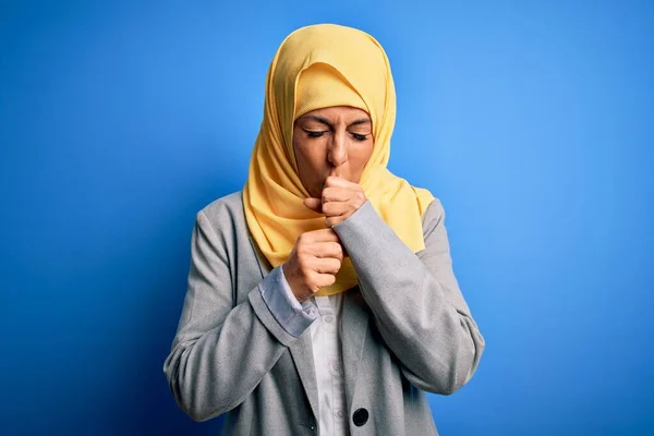 中世のブルネットのビジネス女性は青い背景感にイスラム教徒の伝統的なヒジャーブを身に着けていて 風邪や気管支炎の症状として咳をします ヘルスケアの概念 — ストック写真