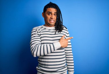 Rastgele çizgili süveter giyen Afrikalı Afro-Amerikan genç adam endişeli ve endişeli, endişeli ve şaşırmış ifadesini bir kenara bırakıyor.