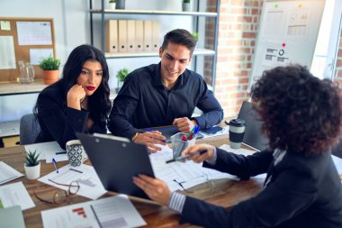 Group of business workers smiling happy and confident. Working together with smile on face reading documents and  speaking at the office