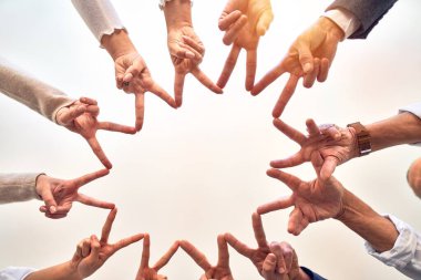 Bir grup işçi ofiste parmaklarıyla sembol çiziyor.