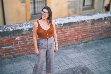 Mutlu ve kendinden emin gülümseyen genç ve güzel bir kadın. Kasaba caddesinde yüzünde gülümsemeyle dikilirken