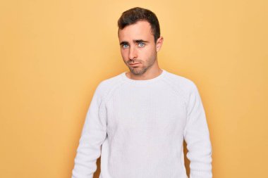 Sarı arka planda dikilen mavi gözlü genç yakışıklı adam yüzünde ciddi bir ifadeyle rahatlamış. Basit ve doğal bir şekilde kameraya bakıyorsun..