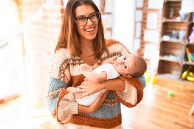 Genç, güzel bir kadın ve bebeği evde duruyor. Anne kucağında ve yeni doğmuş bebeği kucaklıyor.