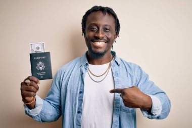 Pasaportlu genç Afrikalı Amerikalı turist. Para transferi için elinde banknotlar var. Sürpriz bir yüz ifadesiyle kendini gösteriyor.