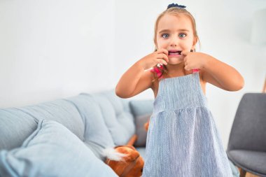 Genç, güzel sarışın kız çocuk anaokulunda oyuncaklarla oyun oynuyor, komik suratlar yapıyor.