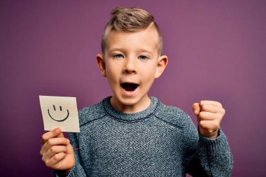 Küçük beyaz çocuk mutlu bir mesaj olarak gülen yüzünü gösteriyor. Gururla bağırıyor, zaferi ve başarıyı kutluyor. Çok heyecanlı, coşkulu bir duygu.