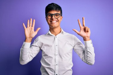 Mor arka planda gömlek ve gözlük takan genç yakışıklı iş adamı sekiz numaralı parmaklarıyla gülümseyerek kendinden emin ve mutlu görünüyor..