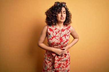 Genç ve güzel kıvırcık Arap kadın tatilde. Çiçekli bir elbise giyiyor. Güneş gözlüğü takıyor. Ache kavramı.