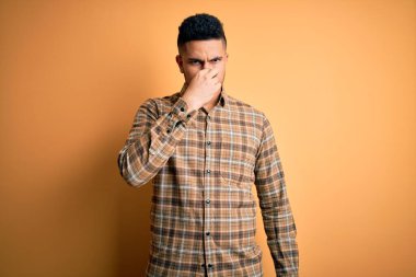 Sarı arka planda duran sıradan bir tişört giymiş genç yakışıklı bir adam pis ve iğrenç bir koku alıyor. Dayanılmaz bir koku. Parmakları burnunda nefesini tutuyor. Kötü kokuyor.