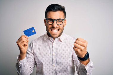 Genç bir iş adamı kredi kartını soyutlanmış arka planda tutarken sinirlenmiş ve sinirlenmiş bir şekilde bağırıyor, çıldırmış ve el kaldırarak bağırıyor.